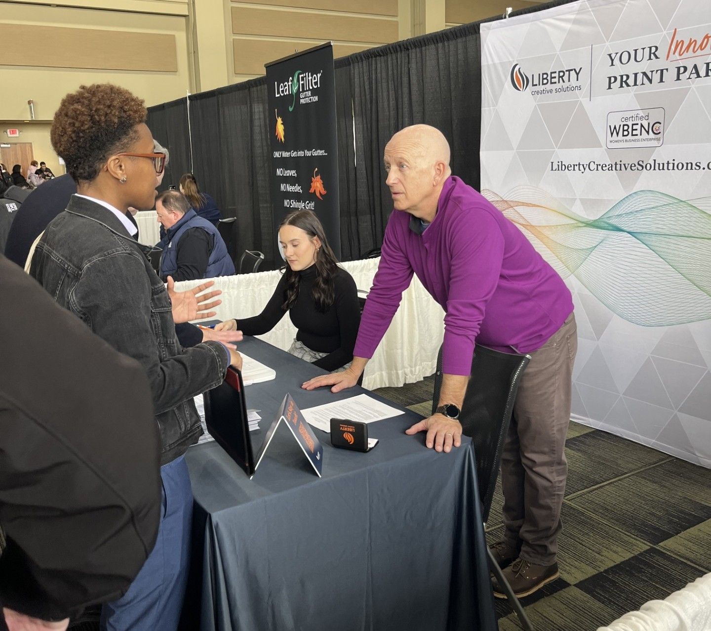 Myranda Dikos and Jeff Hofer talking with event attendees at the Liberty Creative Solutions booth.