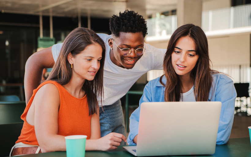 Three diverse college students reviewing targeted email and digital marketing efforts on a laptop.